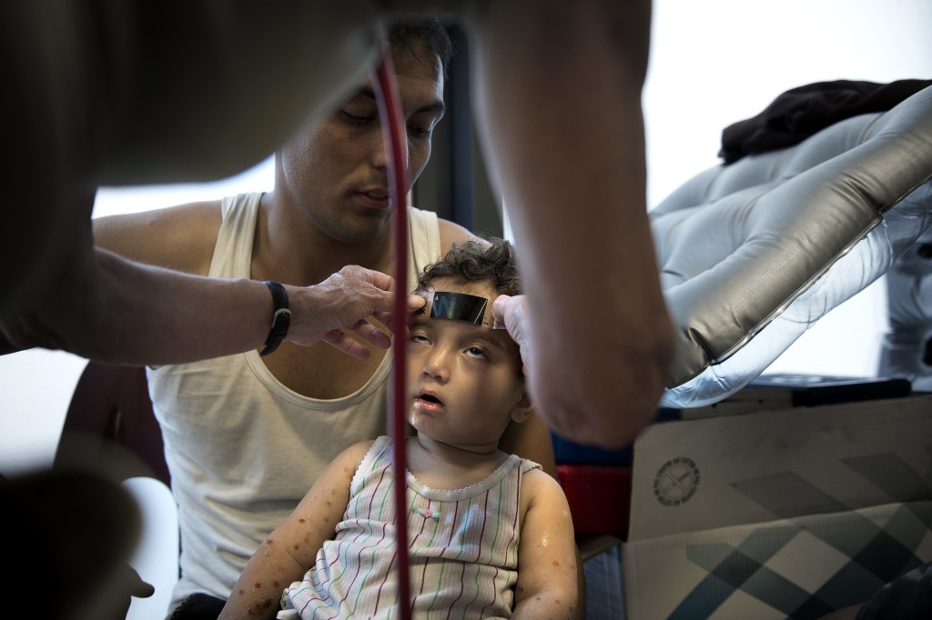German medical student Maria Schtte provides medical assistance to one-year-old Taha Mohamad with her father Lazin Mohamad. (Photo: Newscom)