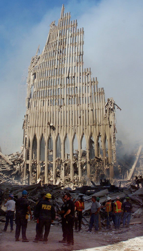 Rescue workers stand next to a piece of wall still standing from the fallen towers in New York September 13, 2001. (Photo: REUTERS/Beth Kaiser/Newscom)