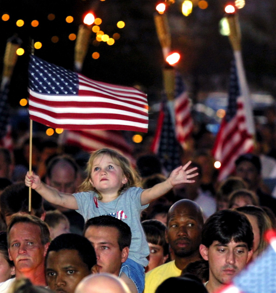 Four-year-old Alana Milawski waves an American flag as she sits on her father’s shoulders during a candlelight vigil held in Las Vegas' Thomas & Mack Center on the campus of the University of Nevada-Las Vegas September 12, 2001. (Photo: REUTERS/Ethan Miller/Newscom)