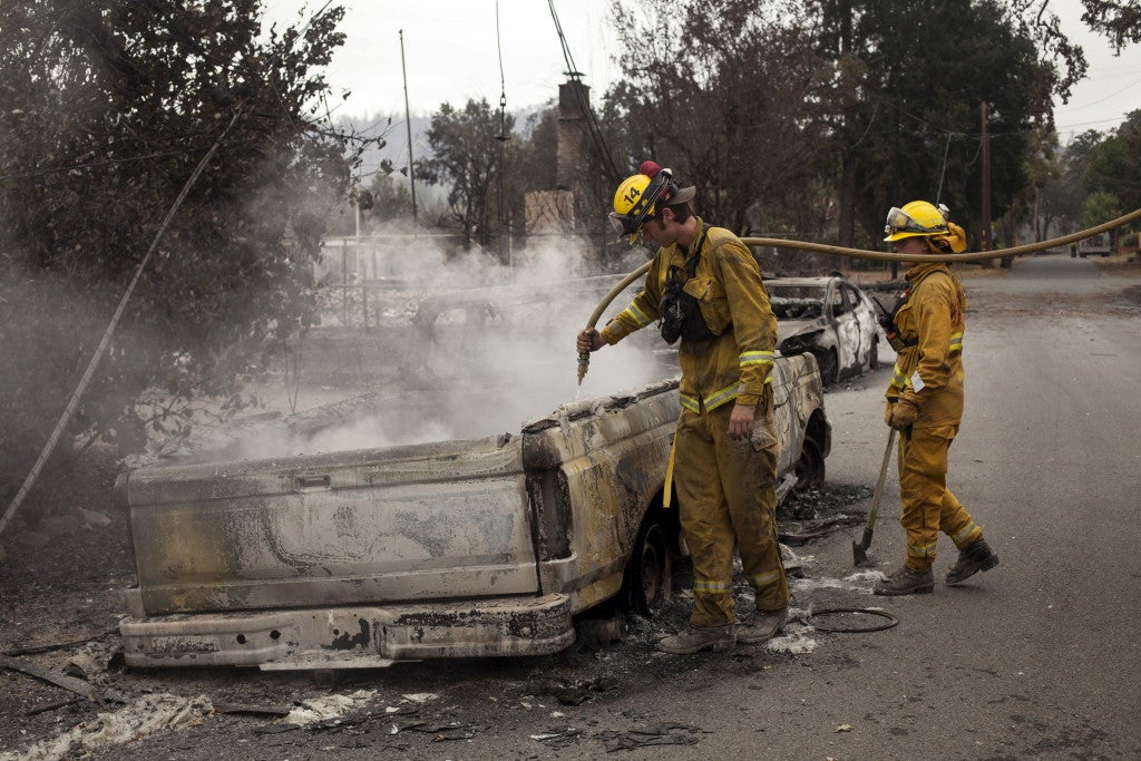 Firefighters extinguish a flare up in an automobile burnt by the Valley Fire near Middletown, California, September 14, 2015. (Photo: REUTERS/David Ryder/Newscom)
