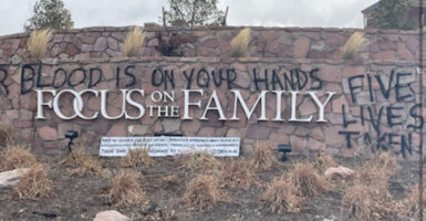Focus on the Family sign with graffiti reading "their blood is on your hands" and "five lives taken"