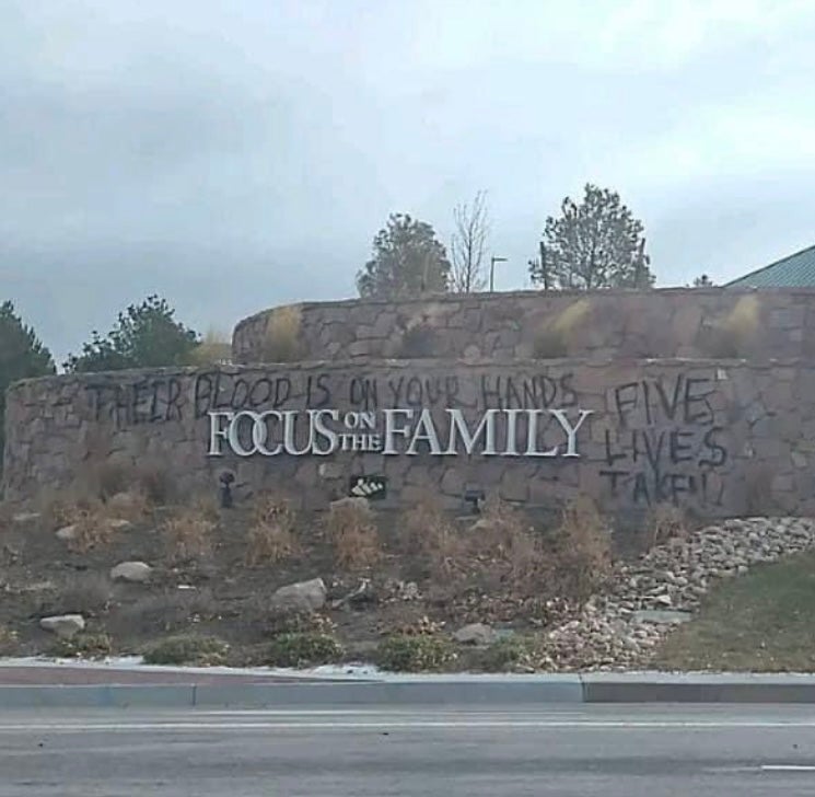 Focus on the Family sign with graffiti reading "their blood is on your hands" and "five lives taken"