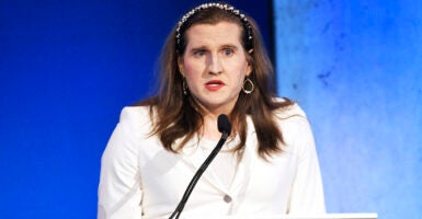 Charlotte Clymer in a white suit before a blue background