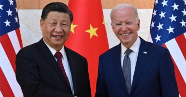 A smiling President Joe Biden and China's President Xi Jinping shake hands