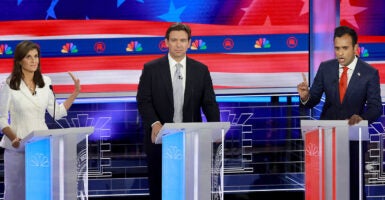 Nikki Haley in a white dress, Ron DeSantis in a black suit, and Vivek Ramaswamy in a blue suit at the third GOP debate in 2024