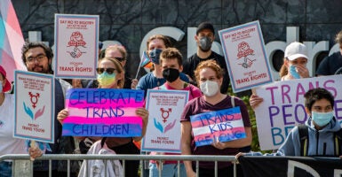 Protesters wearing masks hold signs reading 