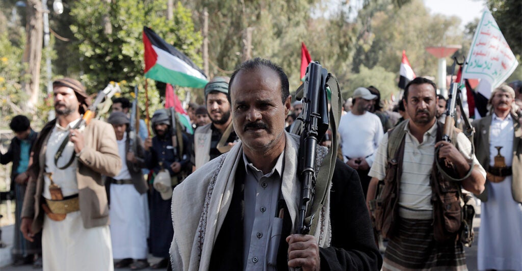 Houthis rebels hold guns and Palestinian flags.