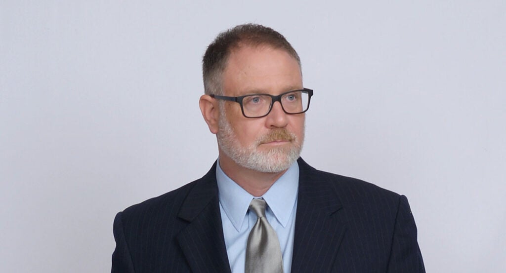 Jeff Younger in a black suit with a silver tie