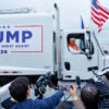 Donald Trump hosts a news conference while seated in a garbage truck with campaign signage on the side