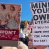 Signs read, "We Won't Go Back" and "Mind your own uterus."