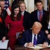 Surrounded by members of Congress and the family of Laken Riley, President Donald Trump signs the Laken Riley Act into law at the White House on Wednesday.