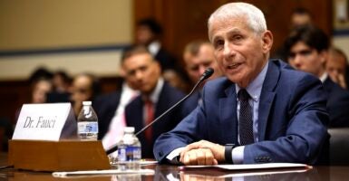 Anthony Fauci sits at a table with a microphone in front of him as he testifies.