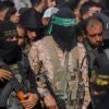 Hamas militants stand while holding machine surrounded by a crowd of people.