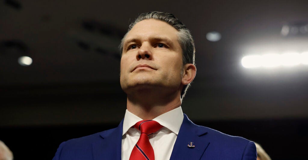 Pete Hegseth wears a blue suit and red necktie.