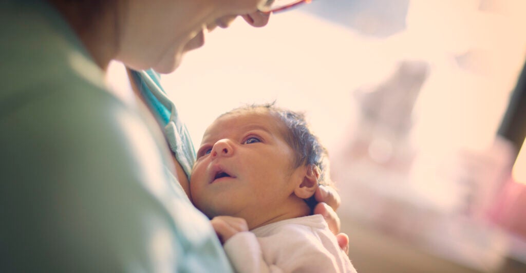 A newborn wearing a white onesie looks up.