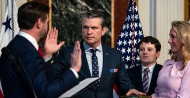 Pete Hegseth raises his right hand and puts his left hand on the Bible.