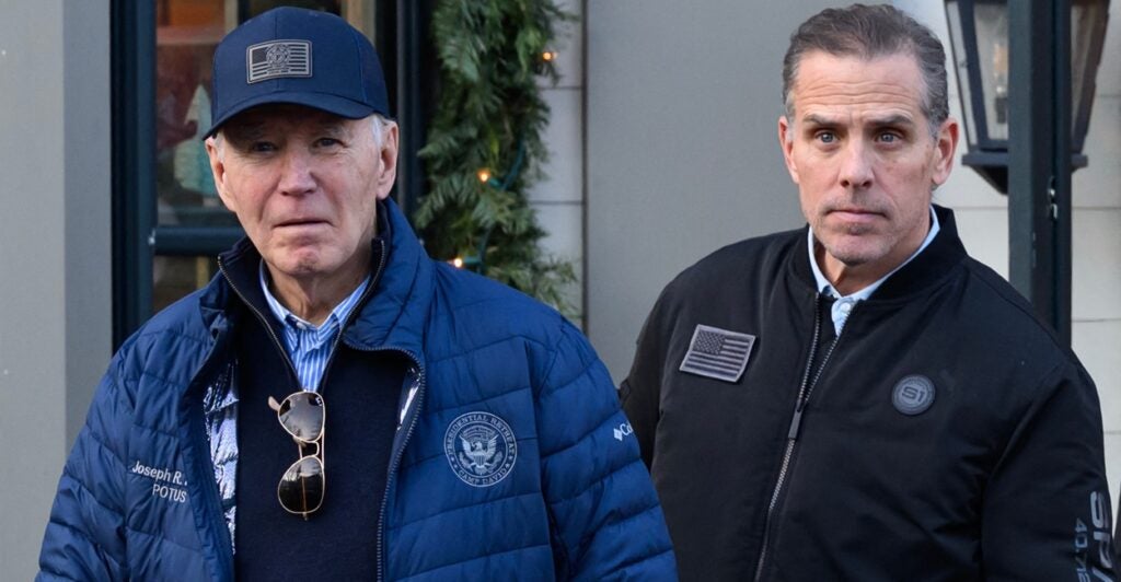 Joe Biden and Hunter Biden stand outdoors next to each other while wearing winter jackets.
