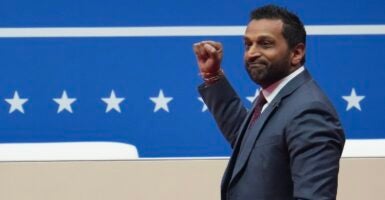 Kash Patel stands with his right hand raised in a fist.