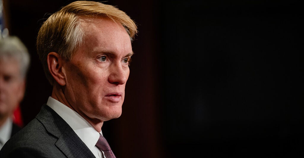 Senator Jim Lankford in a dark suit In a dark room with his side to the camera