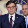 Speaker of the House Mike Johnson stands at a podium and answers questions.