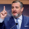 Sen. Ted Cruz raises his finger in a blue suit