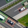 Cars on a highway photographed from the air being tracked electronically with green Or read digital boxes around Each one