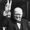 In a three-piece suit and bowtie, British Prime Minister Winston Churchill gives his famous wartime V-sign