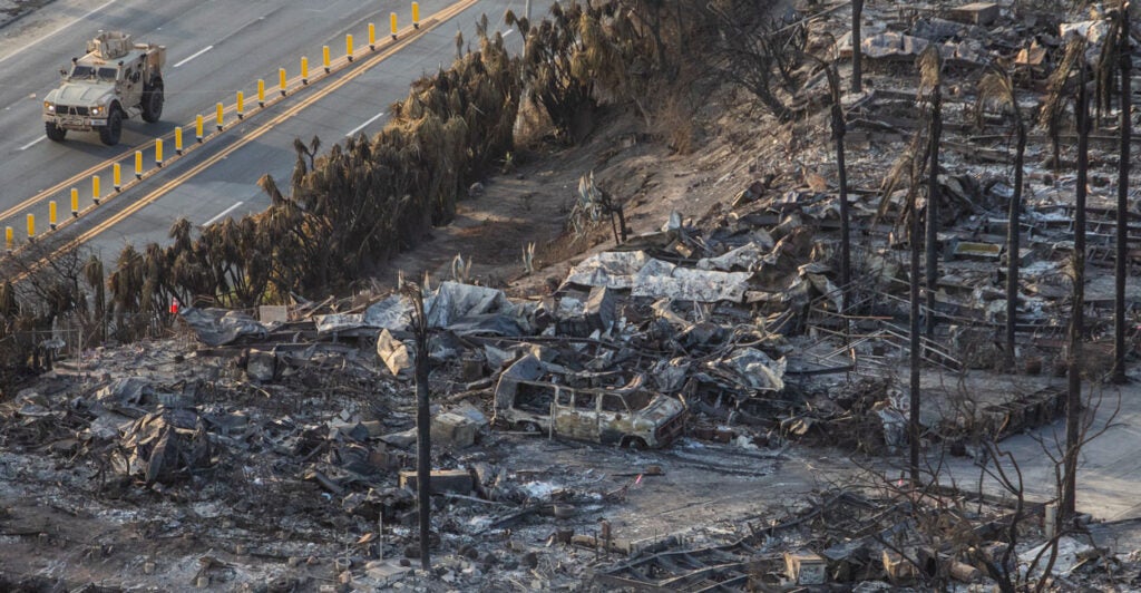 Homes totally destroyed by fire and a National Guard truck on the street next to them