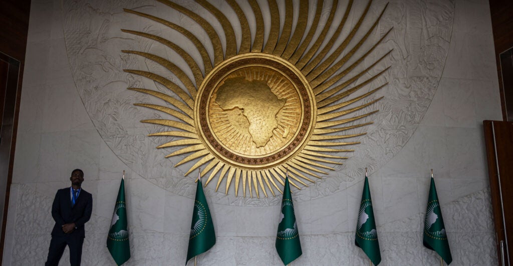 A security guard stands next to an African Union logo in the meeting hall at AU headquarters in Addis Ababa, Ethiopia.