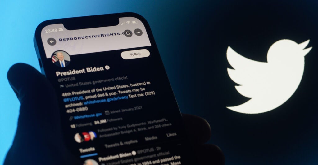 A silhouetted hand holds a cellphone showing then-President Joe Biden's X post in support of abortion.