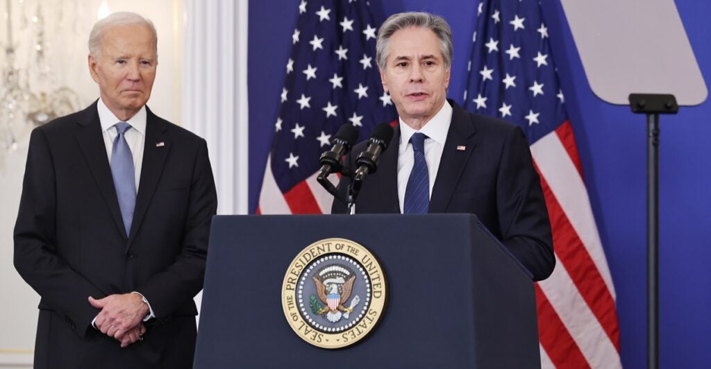 Antony Blinken stands at a podium and looks to his left.