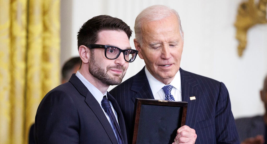 Alex Soros in a suit accepts an award from Joe Biden.