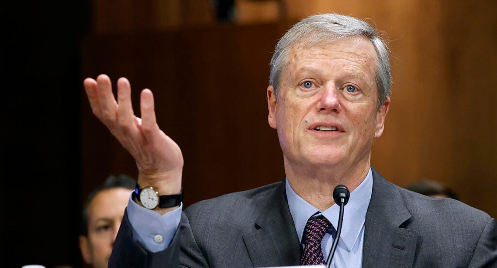 NCAA President Charlie Baker gestures in a blue and grey suit