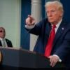 Donald Trump points with his right hand during a press conference while standing at the podium.