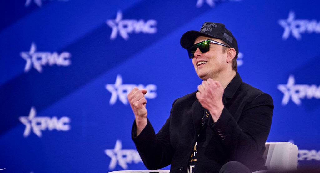 Elon Musk wearing a black Make America Great Again hat speaks at CPAC