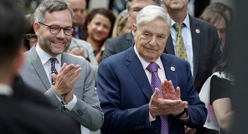 George Soros in a suit claps