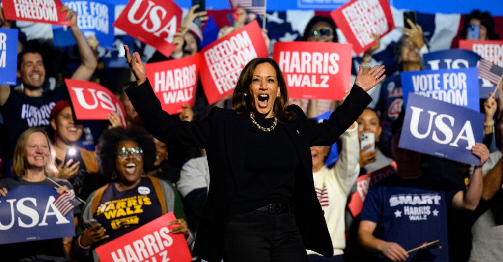 Kamala Harris, dresses in a black dress, stands among supporters for her 2024 presidential campaign.