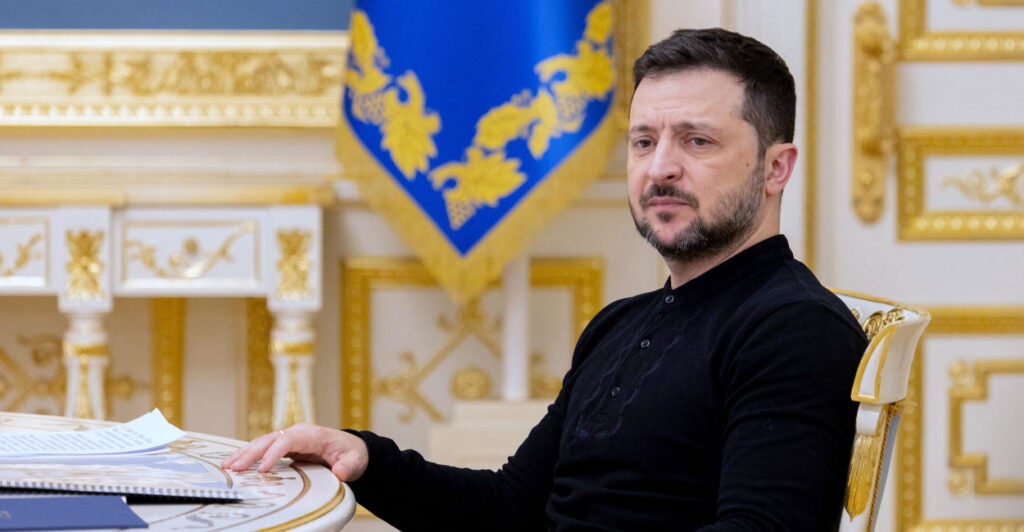 Ukrainian President Volodymyr Zelenskyy sits at a table.