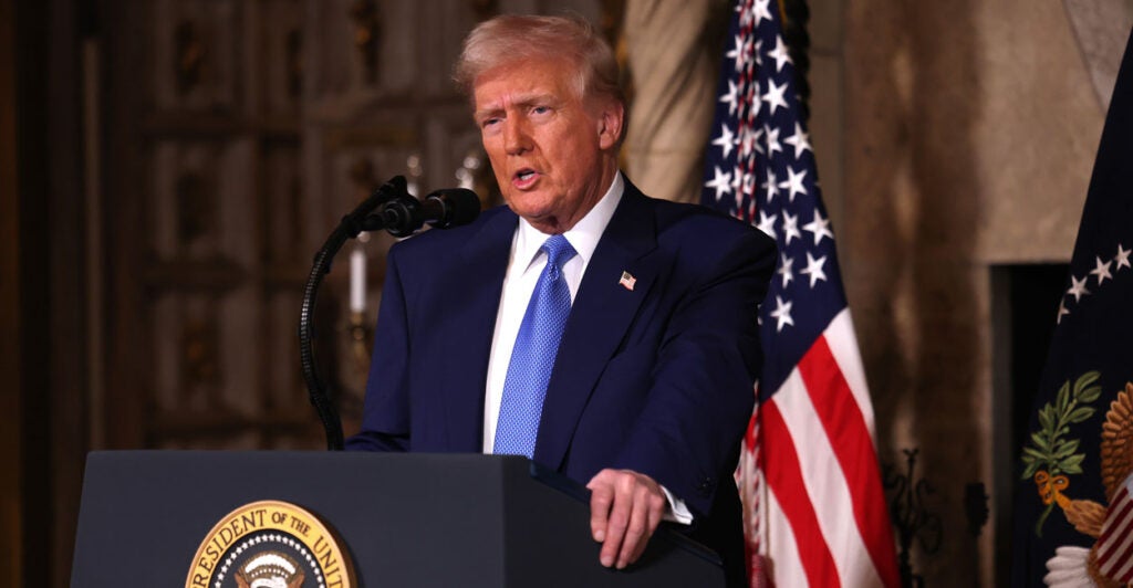 President Donald Trump speaks while standing at a podium.