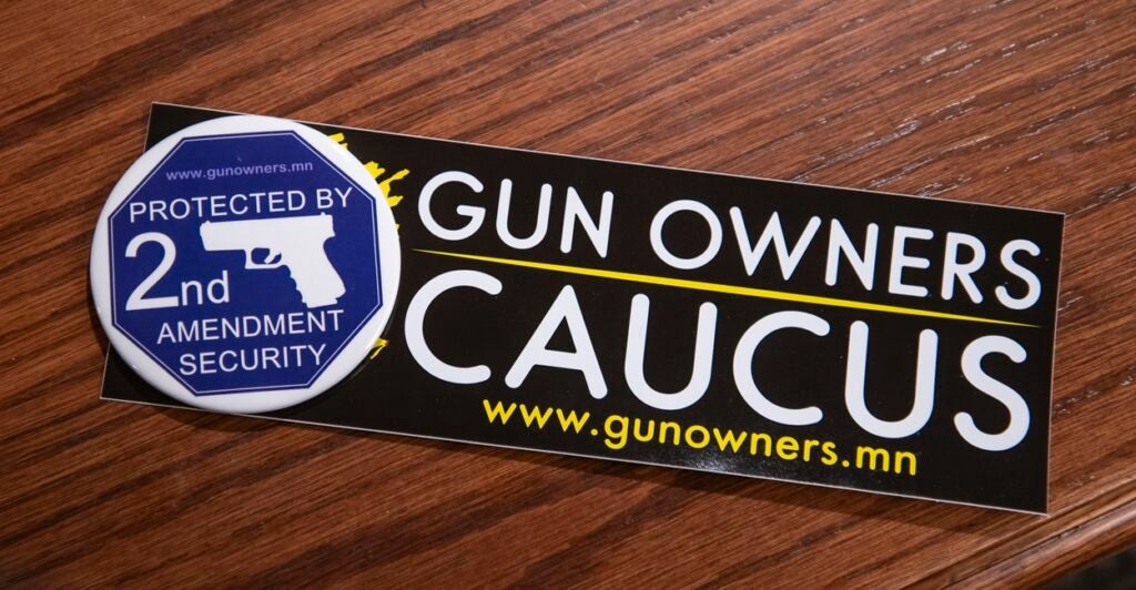 A Second Amendment sticker is on a wood table and it says "Gun Owners Caucus"