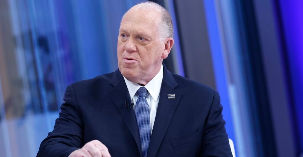 Tom Homan sits while discussing the border and emphasizes his point by pointing with his right hand.