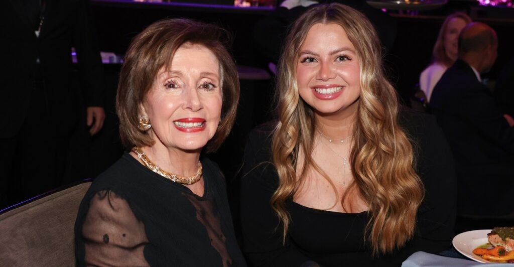 Nancy Pelosi wears formal attire and sits at a table at the Grammy Awards.