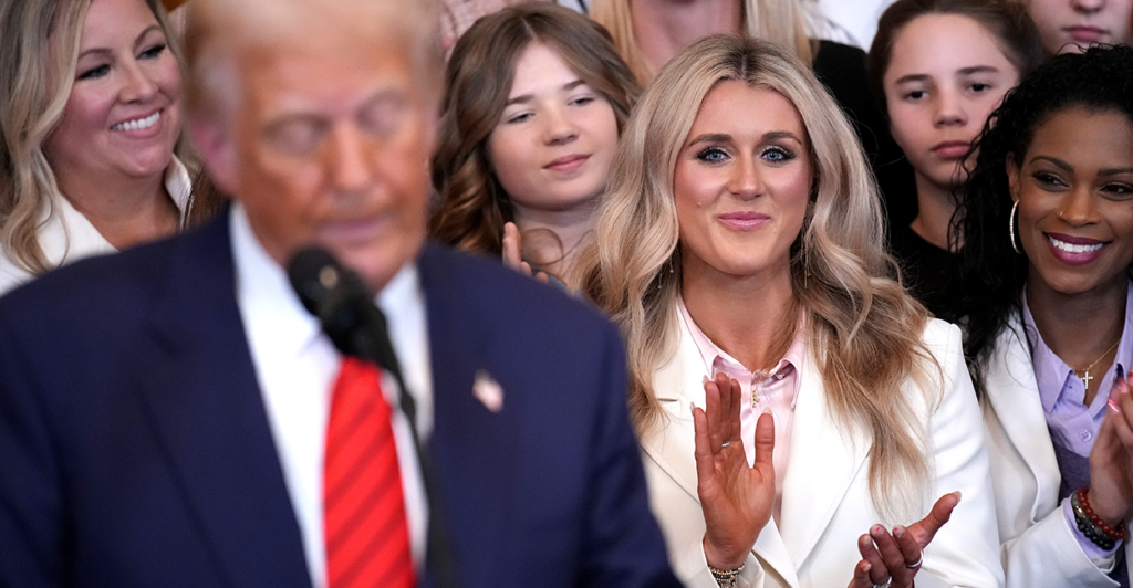 Trump reads from a podium as Riley Gaines and other female athletes applaud behind him.