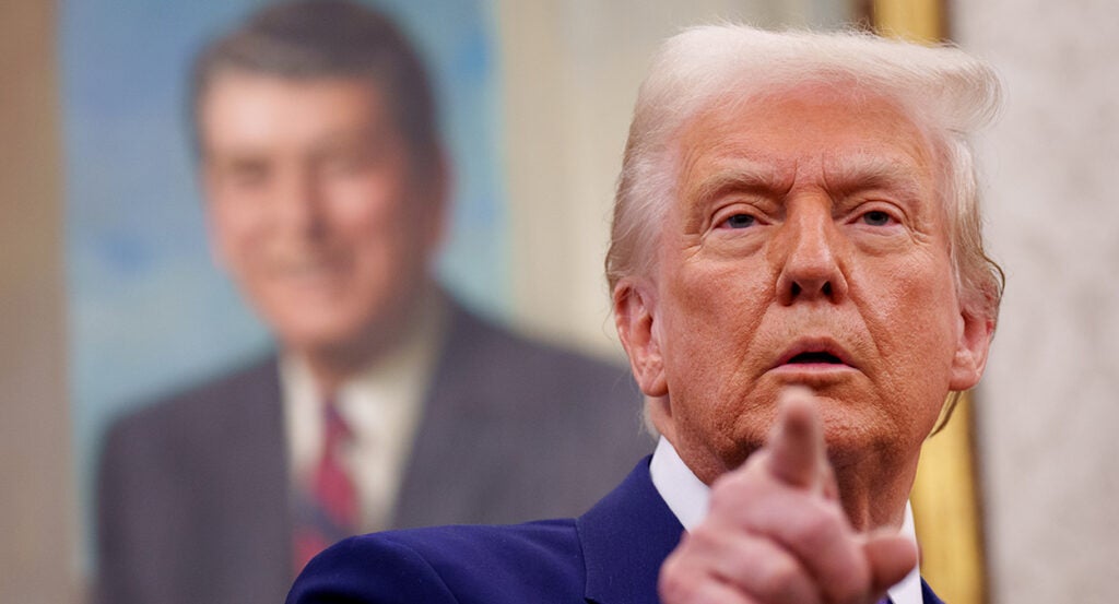 Donald Trump in a blue suit points at the camera