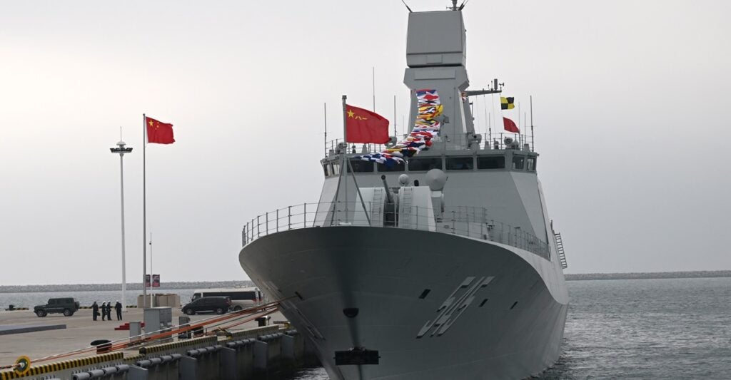 A Chinese navy ship sits at port with a flag flying.