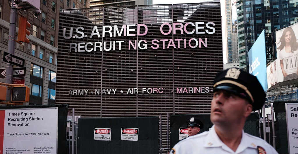 A police officer stands guard as demonstrators gather in New York City's Times Square near a military recruitment center to protest President Donald Trump's reinstatement of a ban on transgender individuals from the military on July 26, 2017.