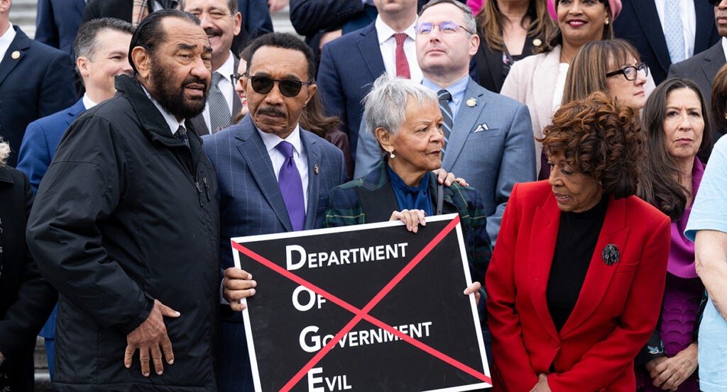 House Democrats stand with a sign reading "Department of Government Evil."