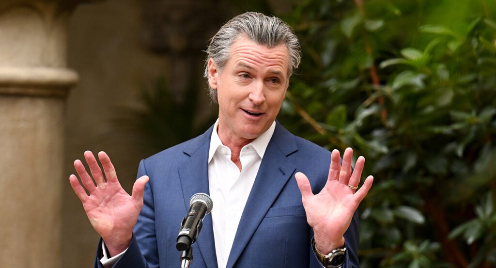 Gavin Newsom in a blue suit shrugs