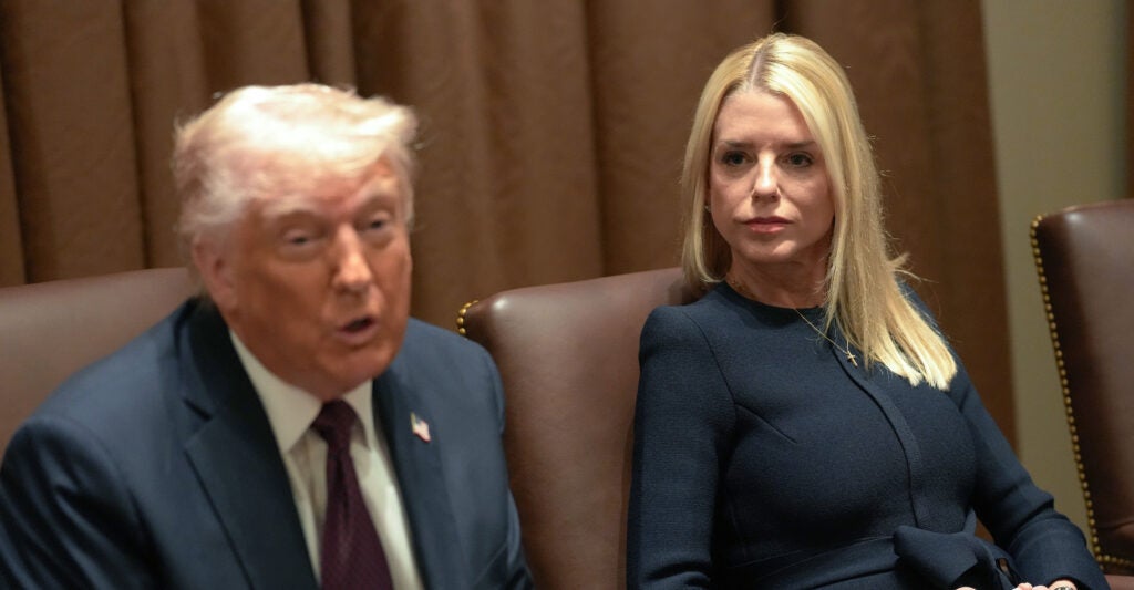Donald Trump, wearing a gray suit and dark necktie, sits next to Pam Bondi, wearing a dark blue dress.