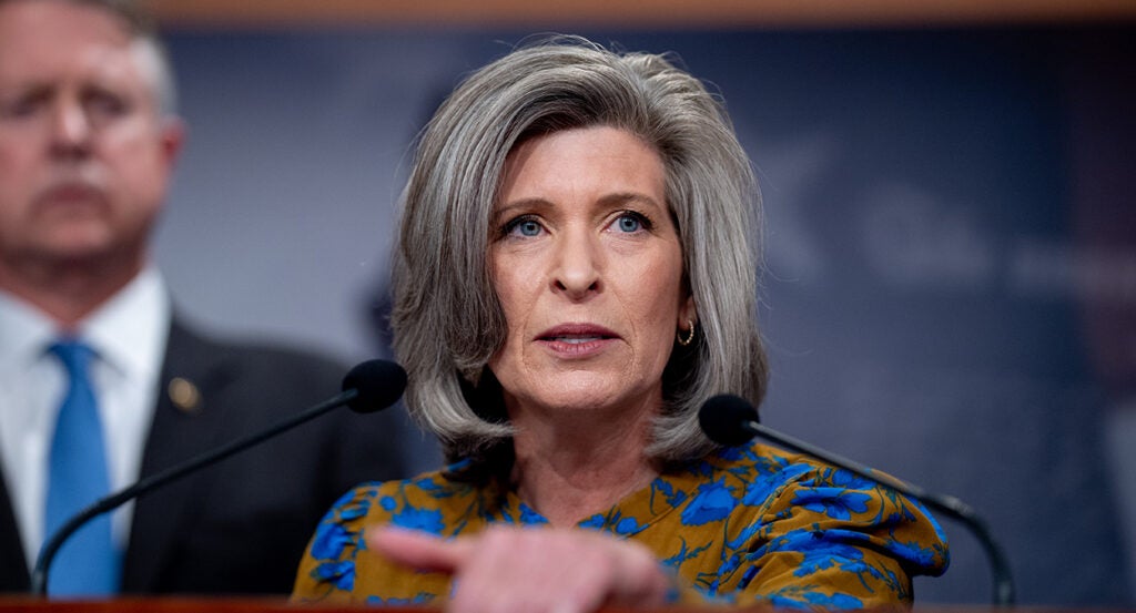 Joni Ernst in a red and blue blouse looking livid